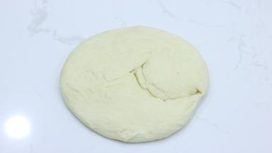 面团取出，轻拍排气，然后用手掌压扁摊开