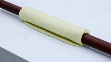 然后翻面，我们翻面的时候需要用擀面杖辅助。不要直接拉扯面团翻面（会破坏已经形成的面团筋度）