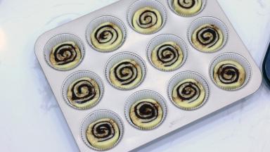 卷好的面团可能会比马芬杯底要大，需要再均匀搓成直径约4~5cm的长条。面团比较柔软，我们需要用锯齿刀分成每个厚度在1.5cm左右的小面团。放入油纸托中