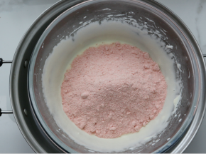 再倒入奶粉和冻草莓粉，用硬刮刀搅拌均匀，或者带上一次性手套将其混合均匀