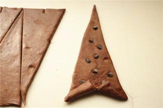 等腰三角形底部再切开一个口子，向两边拉着卷上去，巧克力豆可以这个时候卷进去，记得按一下。