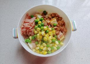 接着将土司丁，火腿丁，火腿丝，玉米粒，甜豆全都放入大碗中；