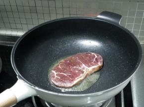 将牛排放入锅中。