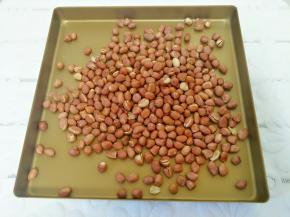 烤好的花生倒在烤盘里，稍凉后双手搓皮