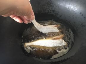 锅里放适量的油，油5、6成热时拎着鱼尾轻轻的贴着油面放到锅里。