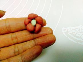 
用牙签取微量的白色面做花蕊，将花蕊固定在花朵中间。一朵梅花大功告成，按此方法，做若干朵梅花。

