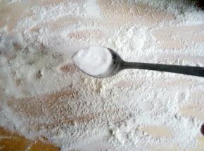 案板上放少许面粉，放小半勺碱面，用擀面杖擀开后和面粉搅匀