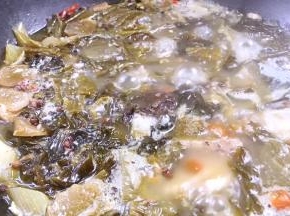 锅内的酸菜鱼骨煮好了，加入盐、胡椒粉和味精拌匀