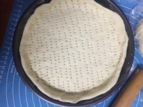 面团擀成圆形，放入披萨盘中，披萨盘要先涂上一层面粉，防粘，用叉子戳上小孔，放入预热好的烤箱180度烤5分钟定型