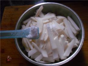 调入2汤匙食用盐，抛匀萝卜条，再用手搓几遍，让盐分尽量渗透萝卜内部，挤出萝卜多余的水分
