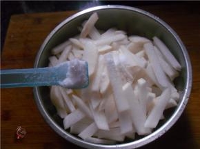 调入2汤匙食用盐，抛匀萝卜条，再用手搓几遍，让盐分尽量渗透萝卜内部，挤出萝卜多余的水分