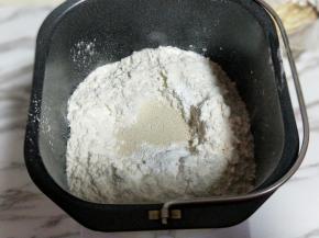 再加入高筋面粉，最后再面粉的顶端挖个小洞，(不要挖到液体) 把酵母粉倒入挖好的洞洞里。再用旁边的面粉将酵母粉盖上。
