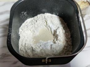 再加入高筋面粉，最后再面粉的顶端挖个小洞，(不要挖到液体) 把酵母粉倒入挖好的洞洞里。再用旁边的面粉将酵母粉盖上。