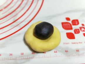 取一块面团，用掌心压扁，当上豆沙馅。