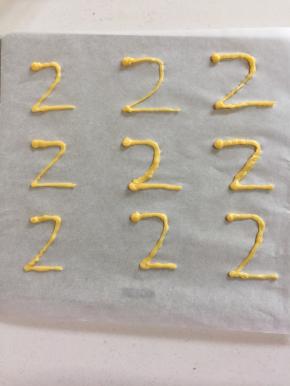 剩下的一点点面糊来做天鹅泡芙的脖子。先在铺了油纸的烤盘上画一个2，正向反向都可以，在顶部多挤一点面糊呈天鹅的头；送入预热好的烤箱中，200度烤6分钟涨发定型，再调到180度烤5分钟即可。要随时守在烤箱旁边观察，颜色差不多了就再把温度调低一点。