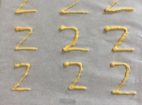 剩下的一点点面糊来做天鹅泡芙的脖子。先在铺了油纸的烤盘上画一个2，正向反向都可以，在顶部多挤一点面糊呈天鹅的头；送入预热好的烤箱中，200度烤6分钟涨发定型，再调到180度烤5分钟即可。要随时守在烤箱旁边观察，颜色差不多了就再把温度调低一点。