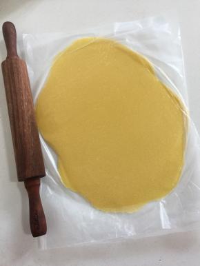 把面团放进保鲜袋中间，先用手按压成饼状，再用擀面杖擀成1~2毫米的面片。千万不要厚了，否则会影响泡芙的涨发；擀好的黄油面皮放在托盘上，入冰箱冷藏变硬后再使用；这个量比较大，可以做几十个，用不完的可以揉成长方形，保鲜膜包好入冰箱冷冻保存，再用时提前取出回温。（酥皮如果在三俩日内用到，可以冷藏；如果长时间保存，揉成方形包起来冷冻，用之前拿出解冻后再擀片。）