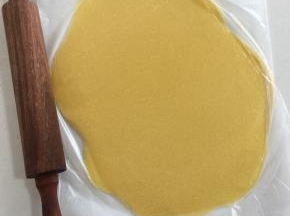 把面团放进保鲜袋中间，先用手按压成饼状，再用擀面杖擀成1~2毫米的面片。千万不要厚了，否则会影响泡芙的涨发；擀好的黄油面皮放在托盘上，入冰箱冷藏变硬后再使用；这个量比较大，可以做几十个，用不完的可以揉成长方形，保鲜膜包好入冰箱冷冻保存，再用时提前取出回温。（酥皮如果在三俩日内用到，可以冷藏；如果长时间保存，揉成方形包起来冷冻，用之前拿出解冻后再擀片。）