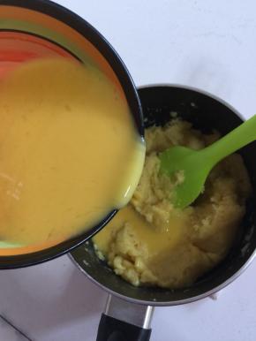 待面团晾至温热不烫手的时候，分几次把搅拌好的蛋液倒进面团中，用硅胶刮刀搅拌。一开始可以多倒一点儿蛋糊，越往后越要少量多次加；材料图中的鸡蛋只出现4个，而实际用了4个半。