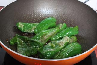 把青椒用锅铲一边压碎，一边翻炒至虎皮；