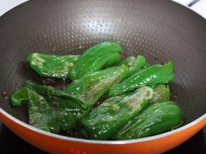 把青椒用锅铲一边压碎，一边翻炒至虎皮；