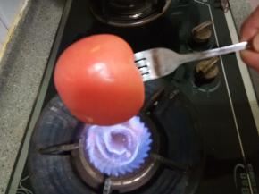 西红柿洗干净，用叉子插上，燃气灶开中火，把西红柿转圈全面的烤一下，至有爆开皮的地方就可以