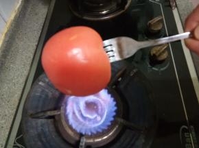 西红柿洗干净，用叉子插上，燃气灶开中火，把西红柿转圈全面的烤一下，至有爆开皮的地方就可以