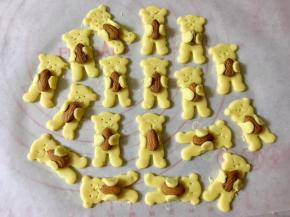 把扁桃仁放在小熊胸前，然后让小熊的两个手臂抱住扁桃仁。