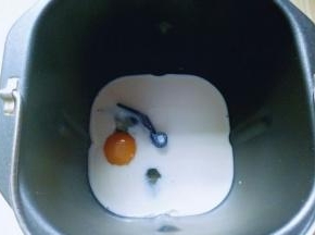 将牛奶倒入面包桶，再加入鸡蛋。