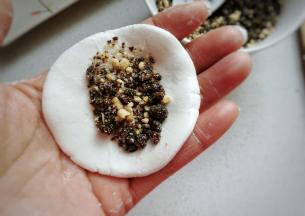 取一份圆面团用手压扁，放上适量馅料；