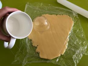 取出冷藏的面团，盖上保鲜膜擀成3mm厚的薄片，找一个比透明盖子稍微大一点的杯子