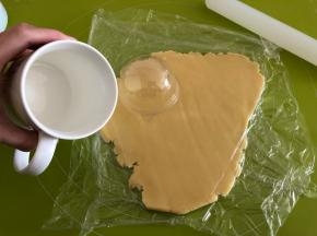取出冷藏的面团，盖上保鲜膜擀成3mm厚的薄片，找一个比透明盖子稍微大一点的杯子