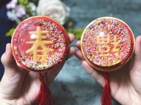 糖霜完全干了以后，在透明盖子里倒入适量彩珠糖，然后再糖霜饼干的周围再挤入一圈红色糖霜，为了粘住盖子，把装了彩珠糖的盖子扣上去，按压一下，等待糖霜干爽即可