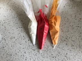 把糖霜分成三份，红色色素和黄色色素分别加入调匀，倒入裱花袋