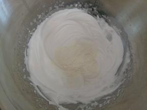 蛋白中加入奶粉和淀粉混合物。用切拌的方式拌匀，不要画圈搅拌以免削泡。