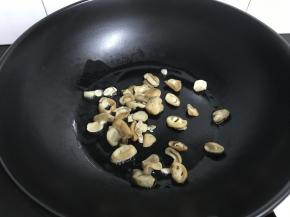 锅中倒入少许油，放入草菇翻炒。