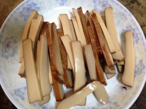 鸡蛋干去包装，先平切成两半，在切成片