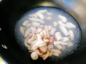 陶瓷炒锅里坐水，先将鱿鱼卷焯水。