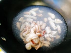 陶瓷炒锅里坐水，先将鱿鱼卷焯水。