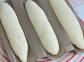 将面团左右捏合住，整形成长条状，放在法棍模上。