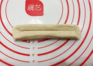 然后两头捏紧捏扁，顺势把面块拉伸长一些；