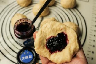 拿一个小面团，按扁成为片状，包入一勺蓝莓果酱。