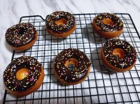 之后将烤好的甜甜圈蛋糕脱模，放入巧克力盘中，沾上溶解的巧克力酱，再立即撒上彩色糖珠，动作要快哈！沾上巧克力后立即撒上糖珠，不然巧克力干了后糖珠容易掉落。