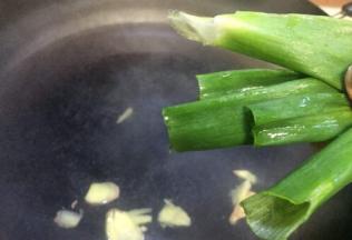 铁锅加水，加两勺料酒再放入姜片大葱节，准备焯排骨的水