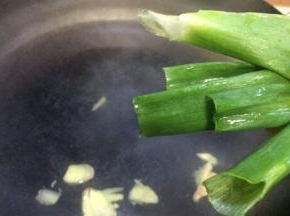 铁锅加水，加两勺料酒再放入姜片大葱节，准备焯排骨的水