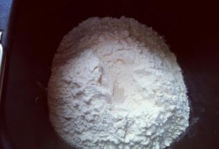 最后放入面粉，再面粉顶端挖个小洞，注意不要挖到液体。把酵母粉放入洞里，再用周边的面粉把酵母粉盖起来。