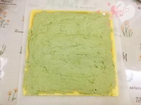 蛋糕片盖上油纸，把油纸和蛋糕片翻过来，切去尾端，抹上抹茶淡奶油；