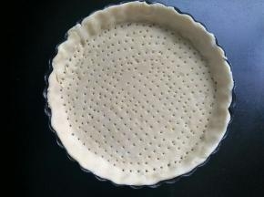 将其中的一个面团幹成圆形，放入披萨盘内，用叉扎小孔。