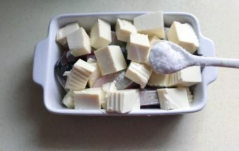 把豆腐盖在鱼的上面，盐均匀撒上去