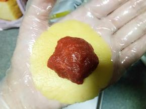 取一个皮料按扁，包入一个馅料，像包月饼一样，慢慢收口团成圆形